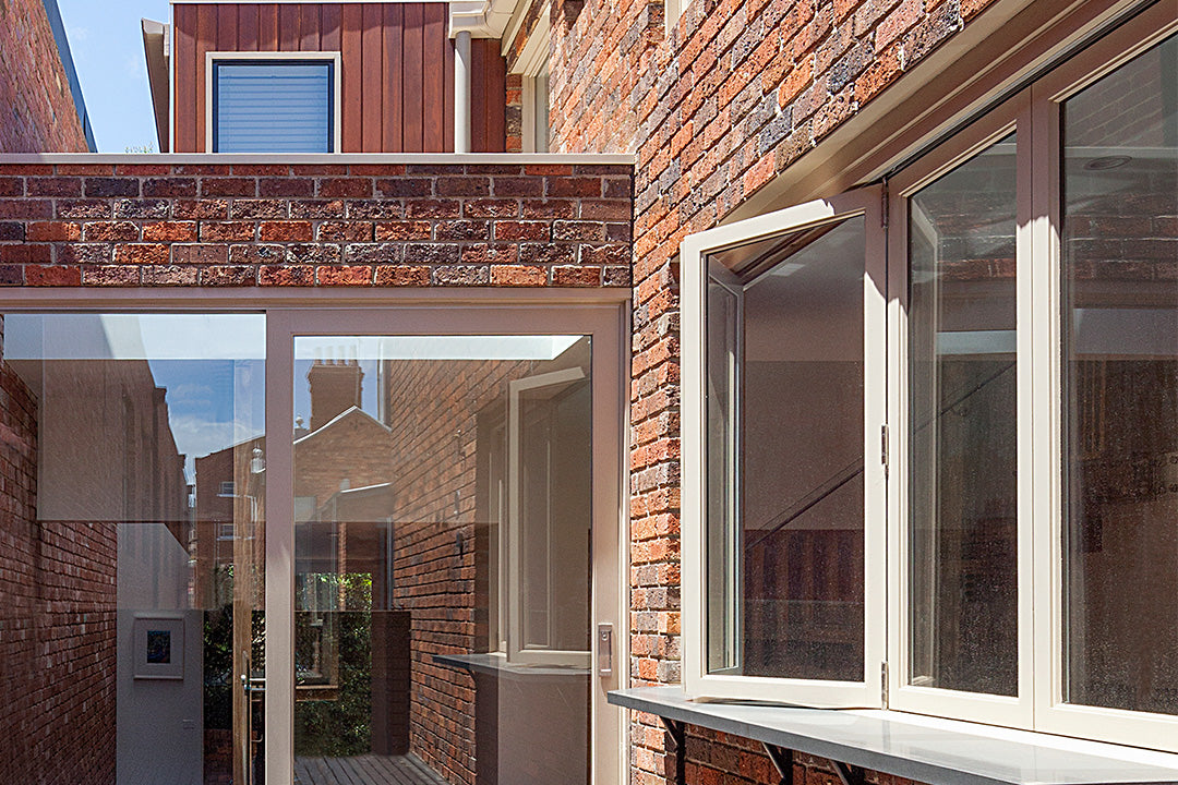 Aluminium bifold windows enhance natural light in a stylish brick wall setting.